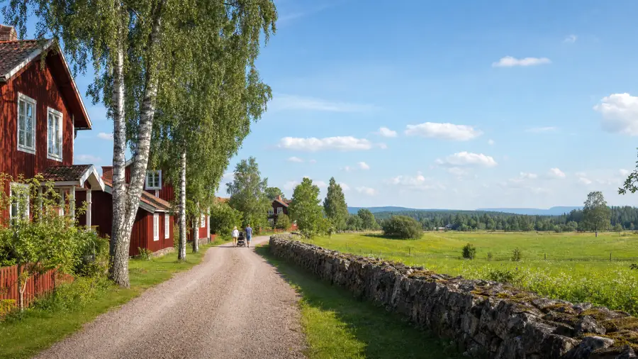 Grusväg genom en by utanför Mora med röda hus, grönska och boendemiljö som känns trygg och lugn.