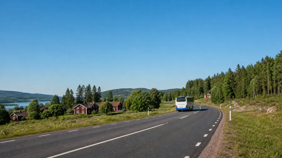 En regional buss fÀrdas lÀngs en vÀlunderhÄllen vÀg i Moras landsbygdsmiljö.