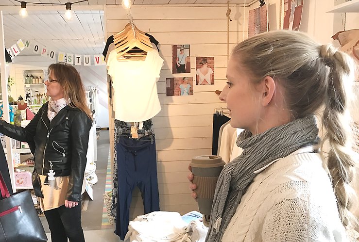 Två kvinnor bland kläder i en affär