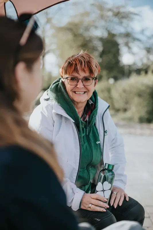 Ingmarie på en bänk med en yngre kvinna i förgrunden till vänster