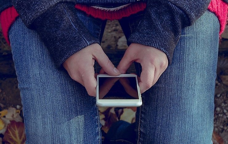 Person som håller mobiltelefon i sitt knä. Foto från Pixabay.
